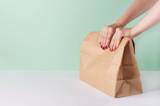 Kobieta trzyma papierową torbę z jedzeniem. Ekologiczne opakowanie i koncepcja usługi dostawy.  - Zdjęcie, obraz