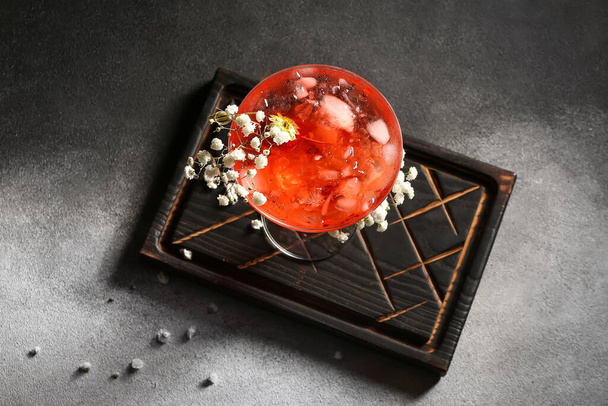 Glas met lekkere cocktail en mooie gypsophila bloemen op donkere achtergrond - Foto, afbeelding