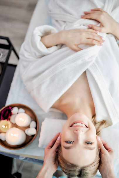 Portrait of fresh and beautiful cute woman taking head and face massage, in spa salon - Photo, Image