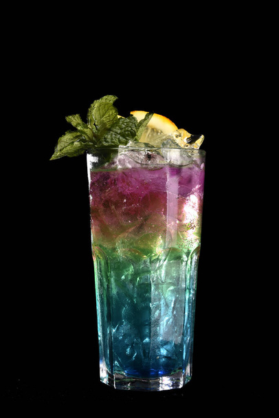 frissítő alkoholos ital bogyókkal, jeges vodkával és ginnel, citromhéj üvegpohárban tálalva a pulton homályos háttérrel - Fotó, kép