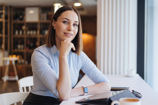 Портрет молодой женщины, улыбающейся, сидя с табличкой в кафе - Фото, изображение
