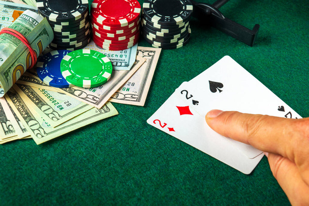 Player points with his finger at a winning one pair combination in a poker game on a table with chips and money in a casino - Foto, imagen