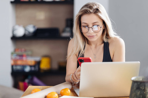 Mladá žena nosí brýle držet telefon v ruce, zatímco textové - Fotografie, Obrázek