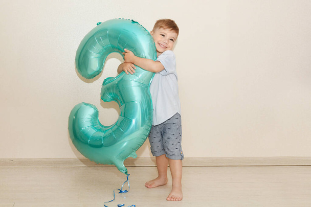 Boy hugs the number three for his birthday - Foto, imagen