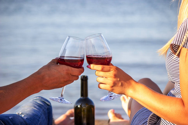 Romanttinen pariskunta nauttimassa viinistä meren rannalla. Valikoiva painopiste - Valokuva, kuva