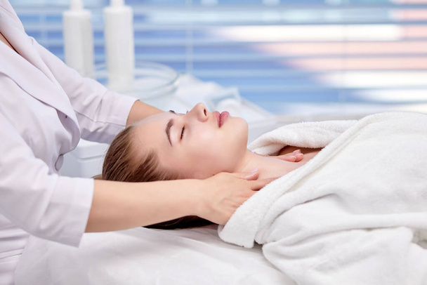 Young Woman enjoying anti aging facial massage. Pretty lady getting professional skin care - Fotó, kép