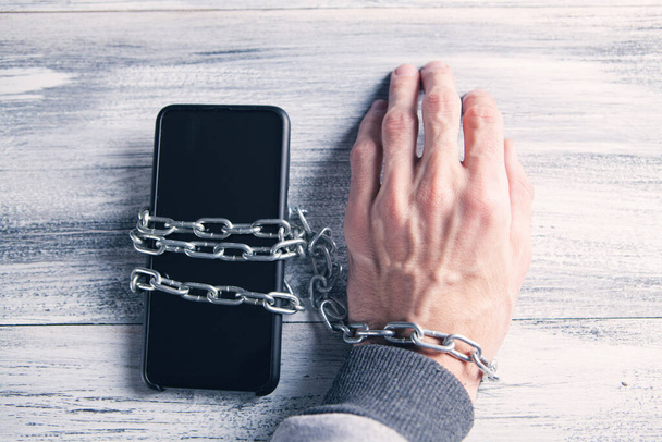 mano atada en una cadena con un teléfono - Foto, imagen
