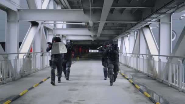 Equipo SWAT caminando por el puente. Soldados militares enmascarados usando rifles  - Imágenes, Vídeo