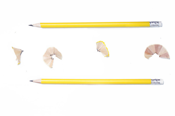 Графитовый карандаш, точилка и стружка на белом столе. - Фото, изображение