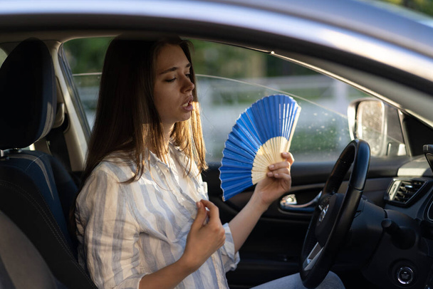 Chica conductor con ventilador de mano que sufre de calor en el coche, tiene problemas con el acondicionador de aire que no funciona - Foto, Imagen