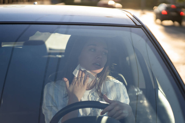 Woman driver being hot during heat wave in car, suffering from hot weather wipes sweat from neck - Valokuva, kuva