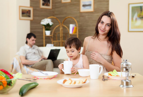 Familia joven en casa comiendo con un bebé
 - Foto, imagen