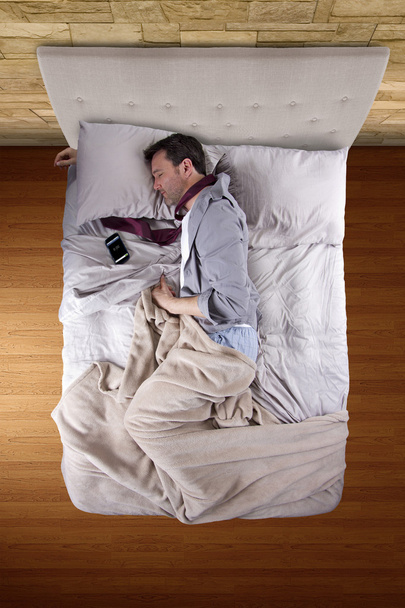 Businessman sleeping with cellphone alarm clock - Foto, Imagen