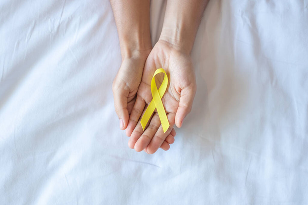 İntihar önleme, sarkoma, kemik, mesane, çocuk kanseri farkındalığı ayı, yaşayan ve hastalıkları desteklemek için sarı kurdele. Çocuk Sağlığı ve Dünya Kanser Günü konsepti - Fotoğraf, Görsel