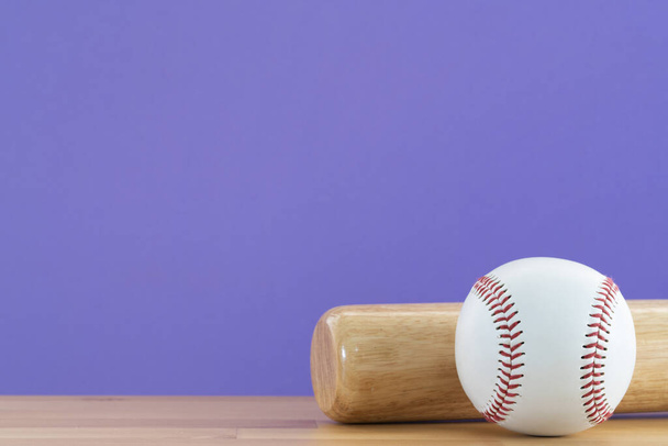 Close up baseball and baseball bat on wooden table with purple copy space background, sport concept  - Foto, Imagen