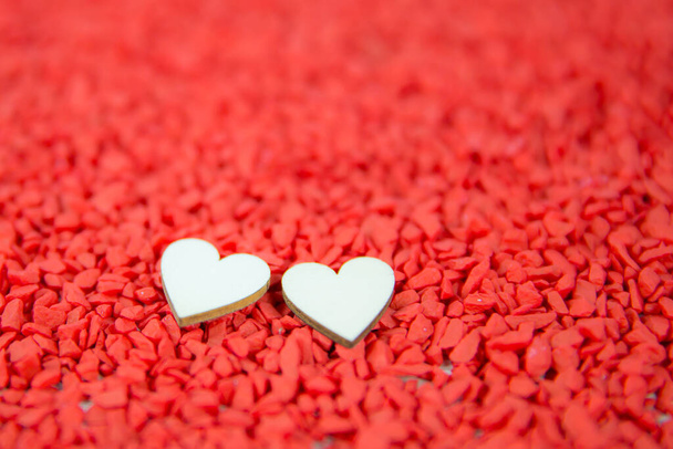 Close-up twee harten voor de liefde symbool op een rode zand achtergrond. Concept de dag van de liefde 14 februari gelukkige Valentijnsdag. - Foto, afbeelding