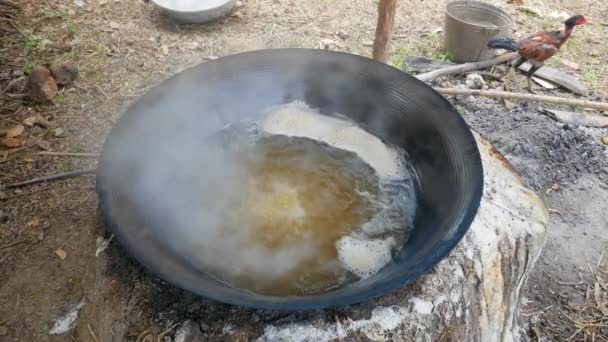 Khmer produttori tradizionali di palma da zucchero. Primo piano dello zucchero liquido bollito sul fuoco in un grande calderone. - Filmati, video