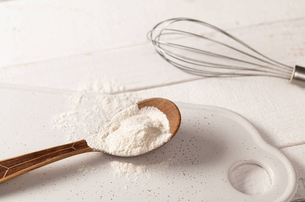 xanthan gum food additive for dough on white plate in wooden spoon with metal whisk - Photo, Image
