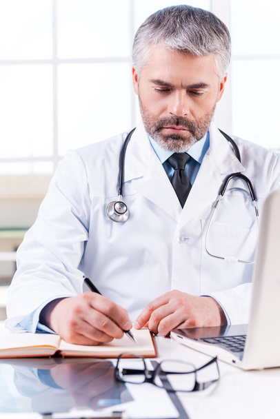 Mature grey hair doctor writing in note pad - Foto, immagini