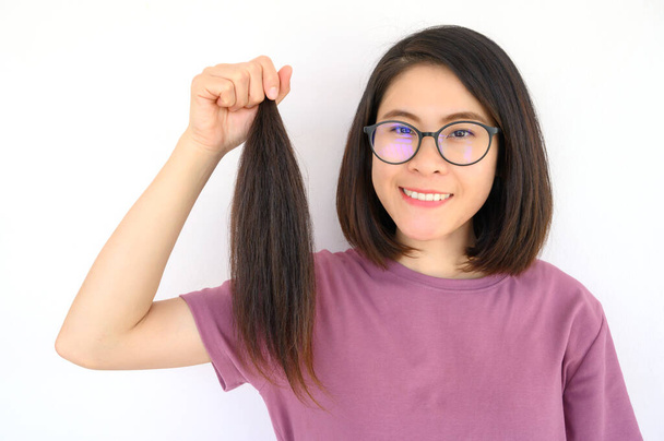 Портрет привлекательной азиатки с хвостиком, стригущей волосы для пожертвования. Пригодные для использования волосы могут превратить ваши длинные замки в бесплатные или недорогие парики для людей с раком. - Фото, изображение