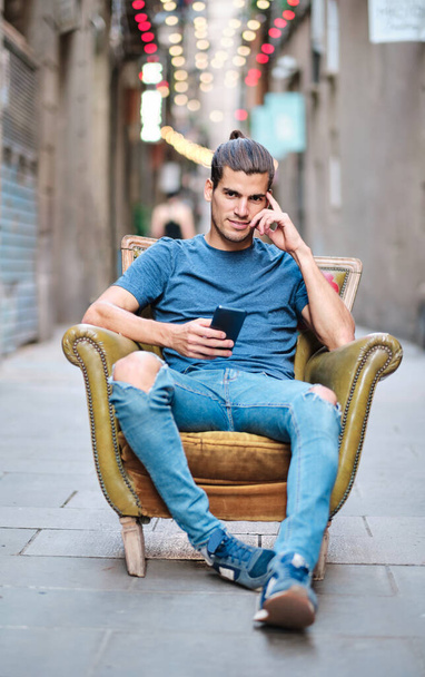 portrait of handsome young man seated on couch at the street at Barcelona - Φωτογραφία, εικόνα