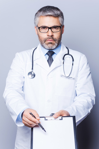 Doctor pointing copy space on his clipboard - Photo, Image