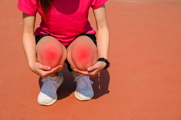 Abgeschnittene Aufnahme einer Läuferin, die sich hinkniet und unter Knieschmerzen leidet. Das passiert oft, wenn die Kniescheibe aus dem Lot geraten ist. Konzepte für häufige Laufverletzungen. - Foto, Bild