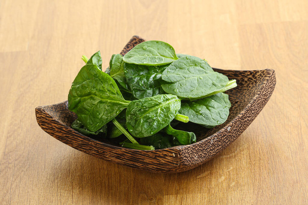 Свежие зеленые листья шпината в миске на деревянном фоне - Фото, изображение