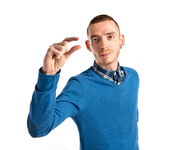 Young man doing a tiny sign over white background  - Photo, Image