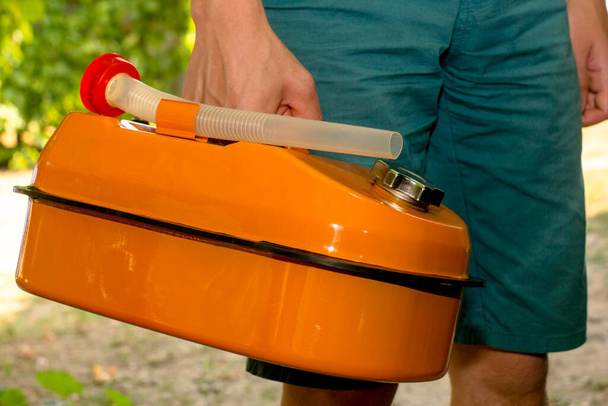 un hombre sostiene un bote de gas naranja en su mano. Foto de alta calidad - Foto, Imagen