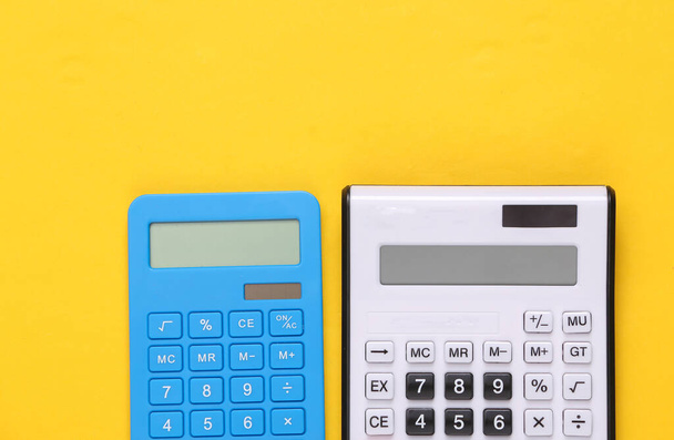 Два калькулятора на жёлтом фоне. Вид сверху - Фото, изображение