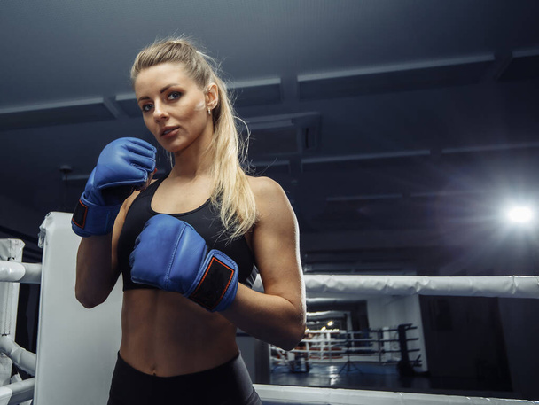 Beautiful young woman in blue boxing gloves in the ring - Foto, immagini