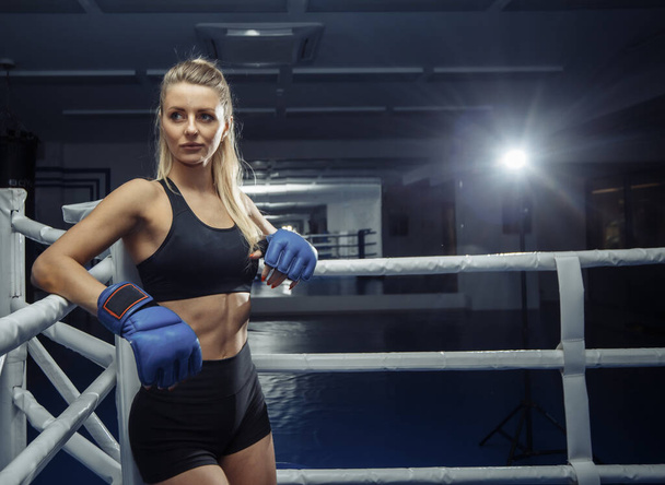 Красивая молодая женщина в синих боксерских перчатках на ринге - Фото, изображение