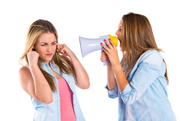 Girl shoutimg with a megaphone at her friend - Foto, imagen