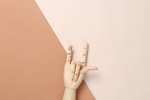 Dřevěná ruka ukazuje rockové gesto na hnědém béžovém pozadí - Fotografie, Obrázek