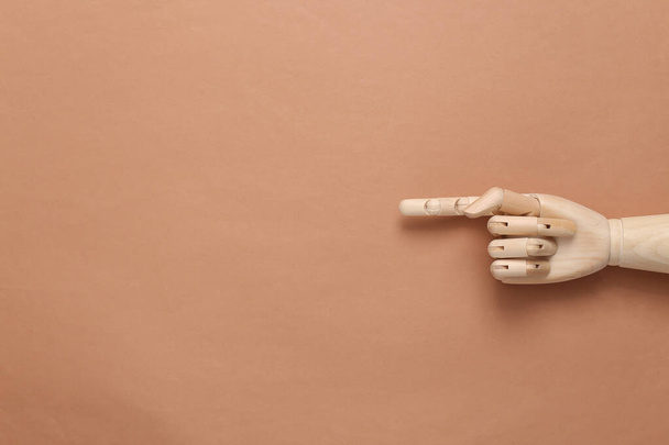 Wooden hand with finger points to empty space on brown background - Photo, Image