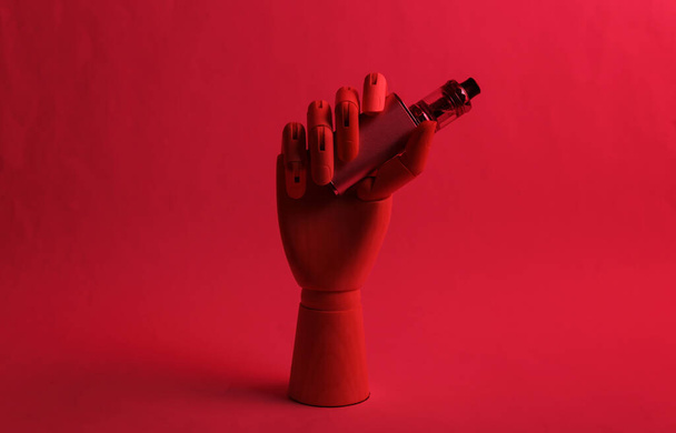 Wooden hand holding vaping device in red neon light - Photo, Image