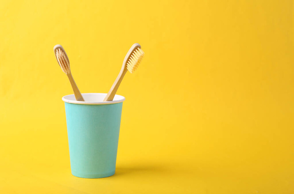 Two Bamboo eco toothbrushes in cup on yellow background - Foto, immagini