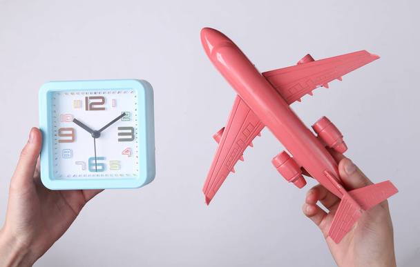 Hands holding alarm clock and plane on white background. Travel time - Photo, Image