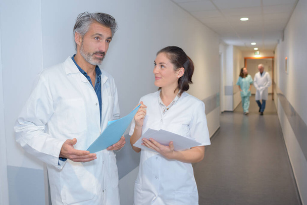 male doctor and female nurse in hospital corridor - Фото, изображение