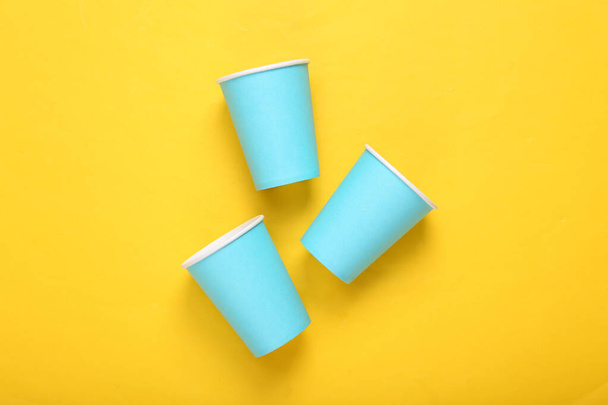 Пустые синие картонные кофейные чашки на желтом фоне. Минимализм - Фото, изображение
