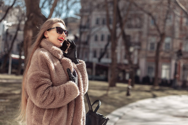Nuori houkutteleva muoti blondi nainen pukeutunut turkki ja aurinkolasit puhuu puhelimessa kaupungissa  - Valokuva, kuva