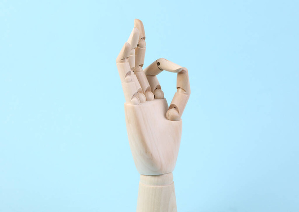 Wooden hand shows okay gesture on blue background - Photo, Image