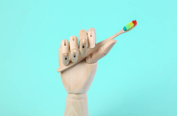 Dřevěné ruce drží zubní kartáček na modrém pozadí - Fotografie, Obrázek