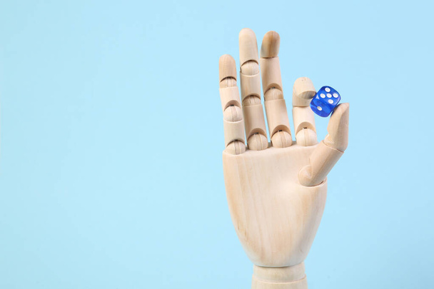 Wooden hand holding dice on a blue background - Photo, Image