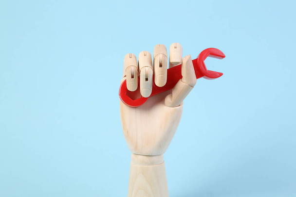 Dřevěné ruce drží klíč hračky na modrém pozadí - Fotografie, Obrázek