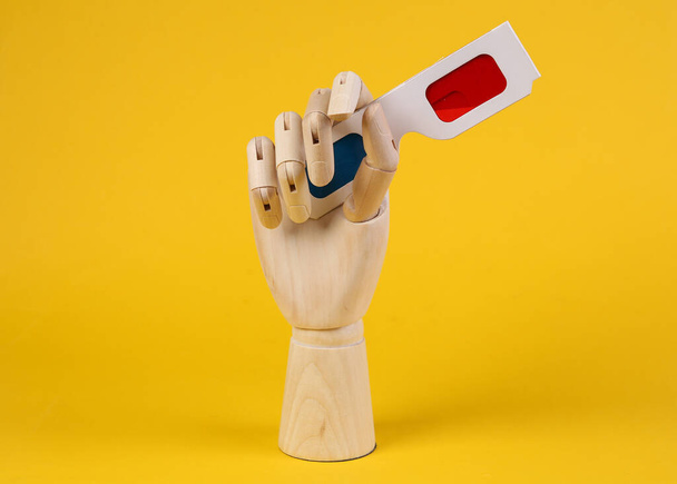 Wooden hand holds 3d glasses on yellow background - Photo, Image