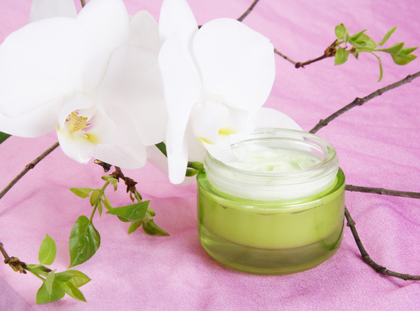 Crème hydratante pour le visage avec orchidée blanche sur tissu violet
 - Photo, image