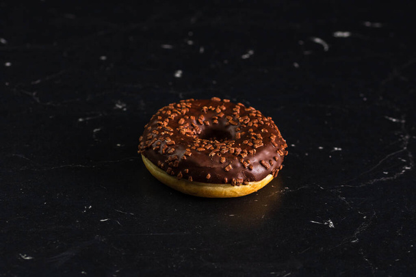 A chocolate glazed donut with chocolate chips isolated. Close up of delicious donut. - Fotó, kép