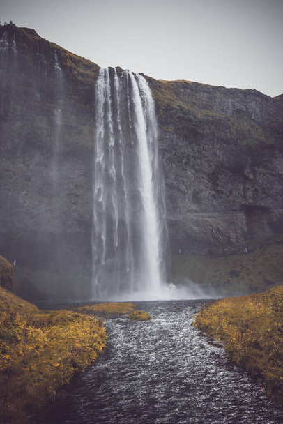 A vertical shot of the Seljalandsfoss waterfall on a gloomy day in Iceland - Fotó, kép